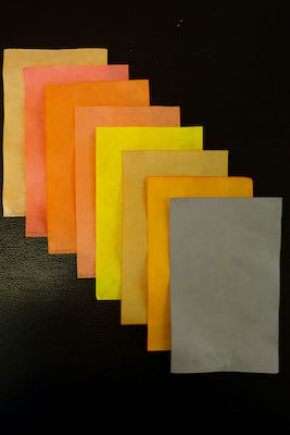 Eight sheets of paper dyed in shades of yellow, orange, pink and grey