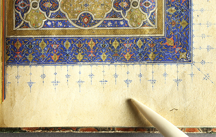 A pointer positioned on a portion of a manuscript illuminated with gold and ultramarine