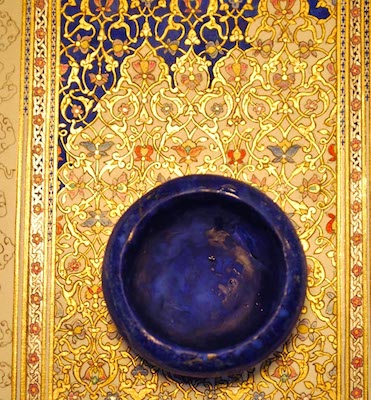 A pot of ultramarine paint positioned on top of a portion of a gold illuminated manuscript