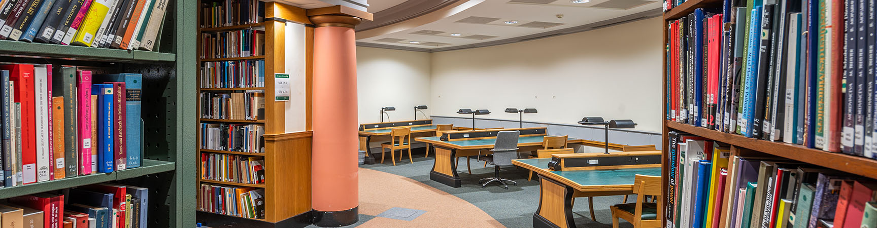 A view of a reading room with three desks curving around a round room with shelves on either side