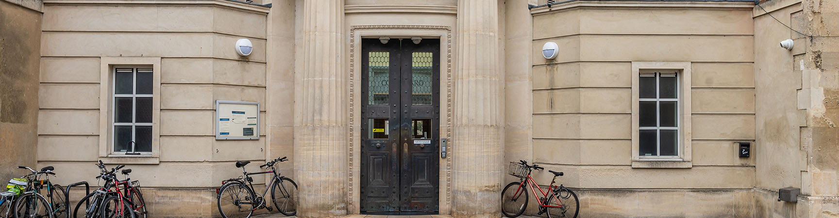 A pale stone building with two large brown metal downs - the outside of the library