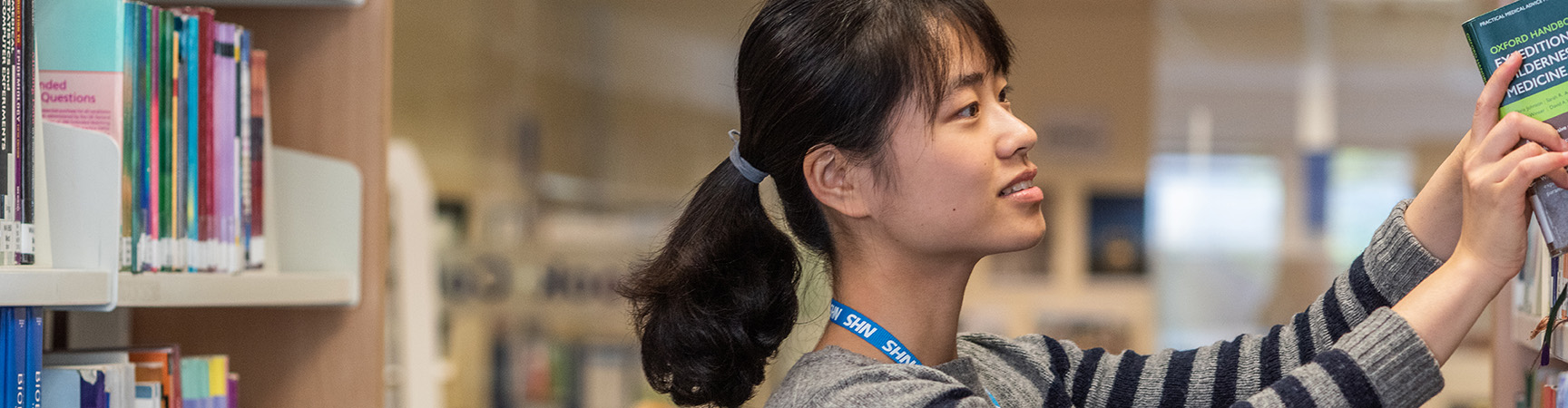 A student retrieves a book from a shelf