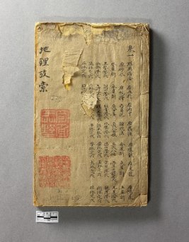 A yellow page covered with Chinese characters - it has rips on the page, and notches of missing paper on the side