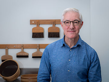 A man in a blue shirt with white hair and glasses