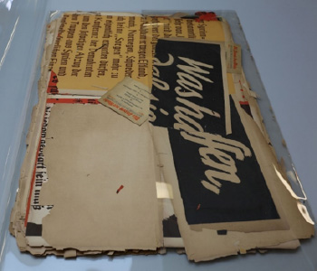 A pile of old posters in a clear protective cover - they are pale background with glimpses of black text