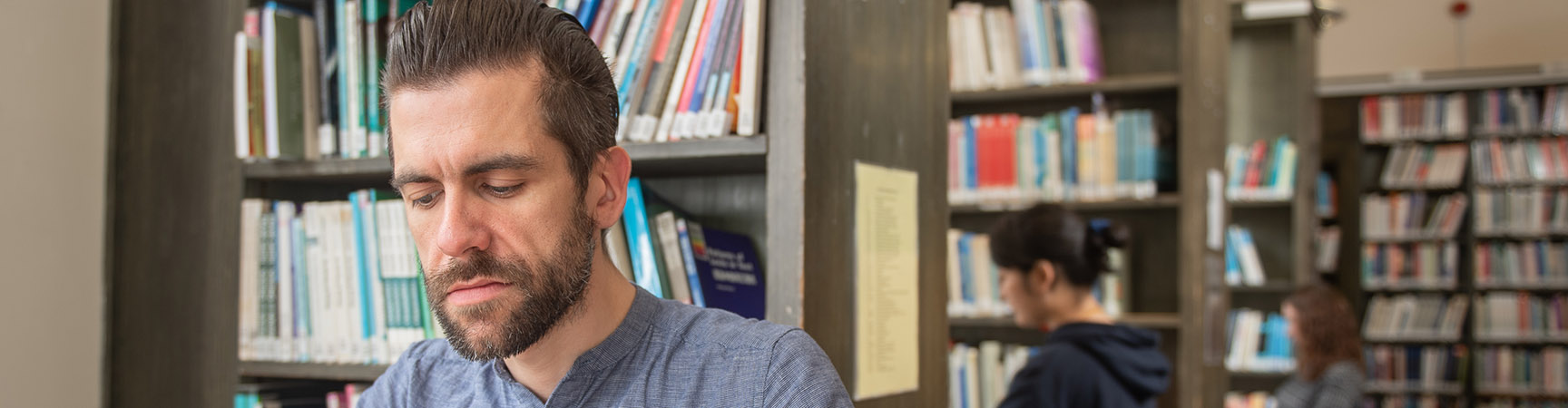 A student working at a desk sitting in front of a bookshelf