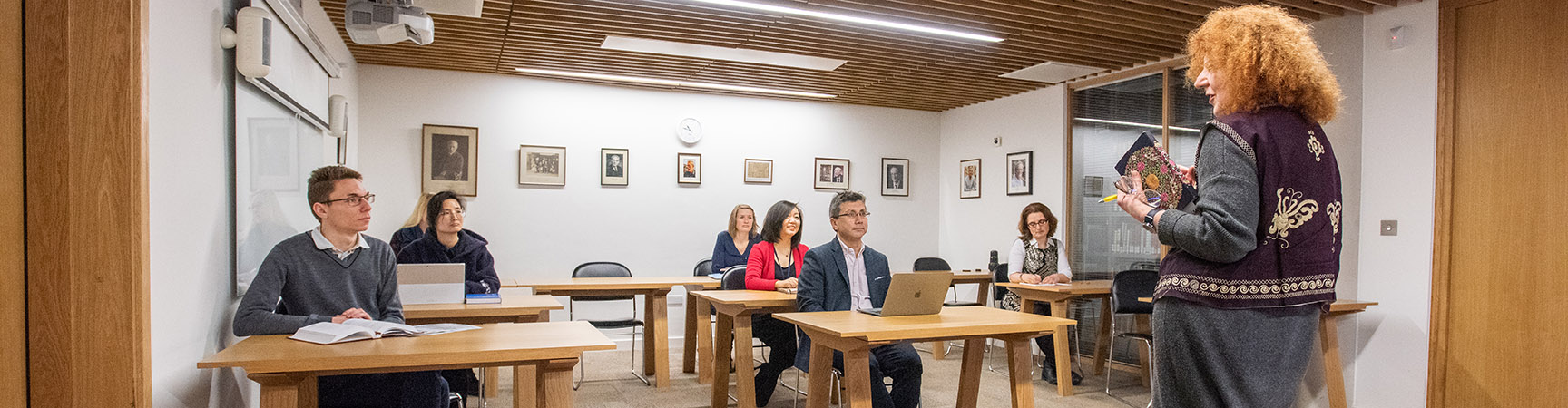 Five students at individual desks being lectured at by a tutor