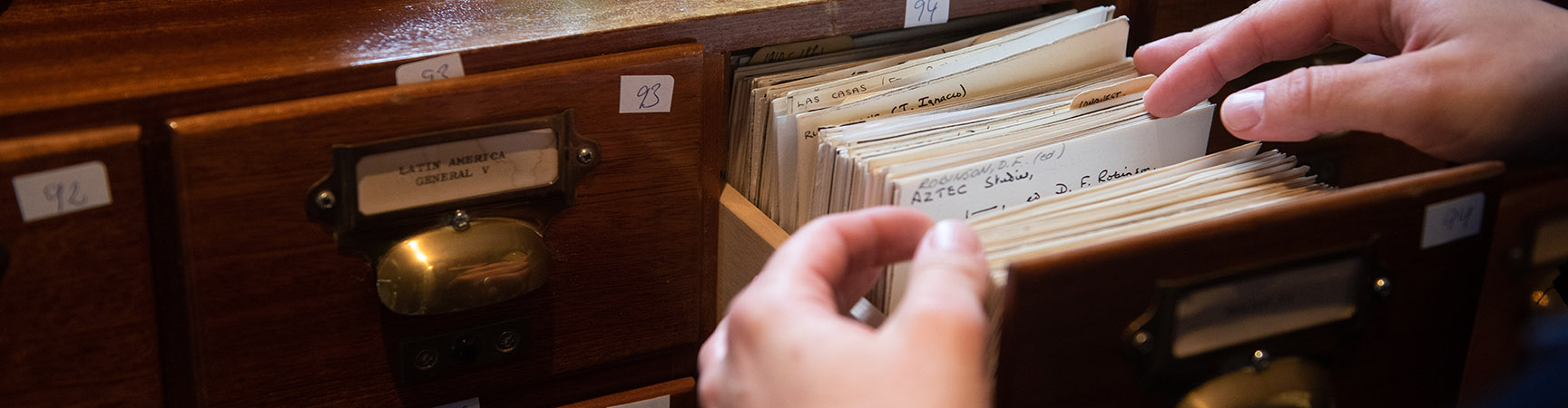 A pair of hands flicking through a card catalogue