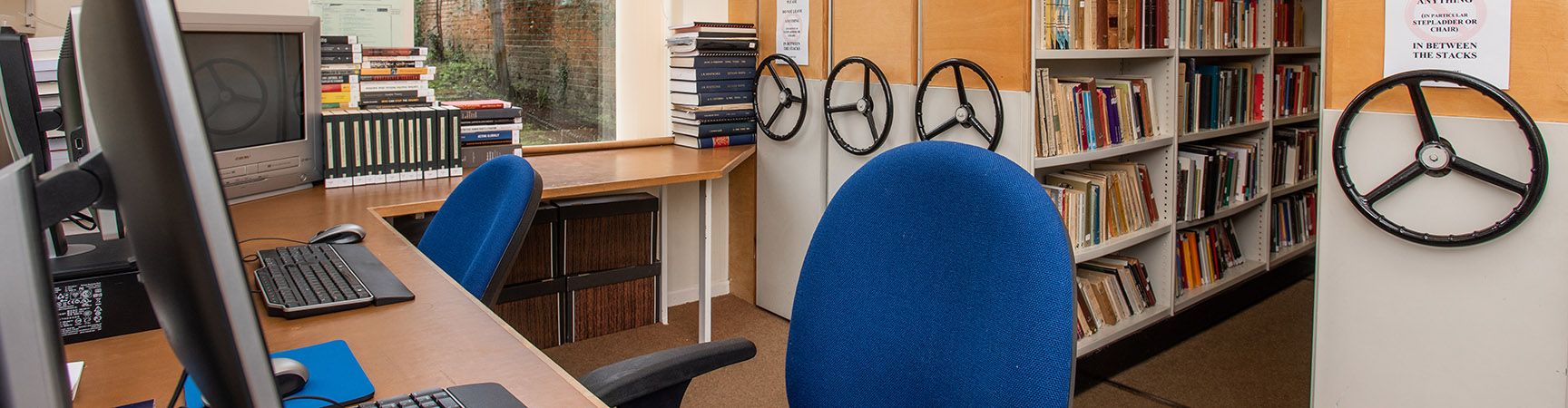 Two computers in front of four rolling bookshelves