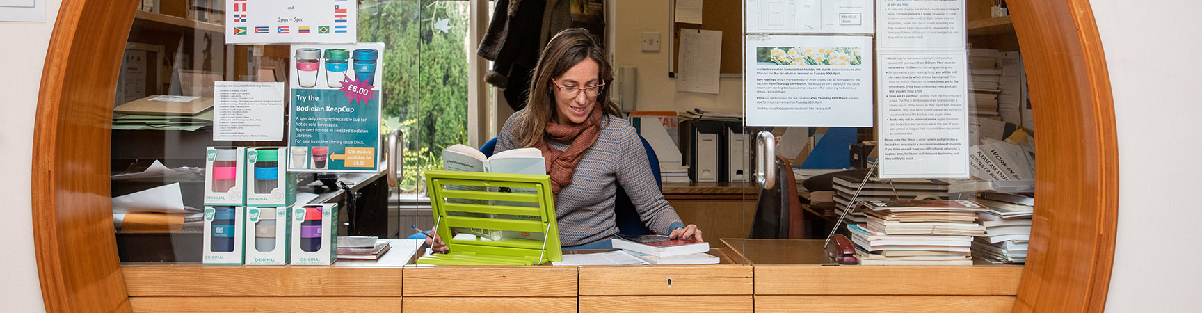 A librarian sitting behind a desk surrounded by a circular window