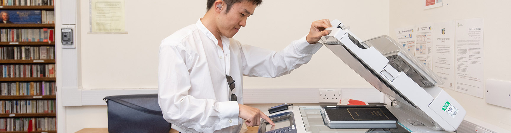 A student opening the top of a photocopier / scanner