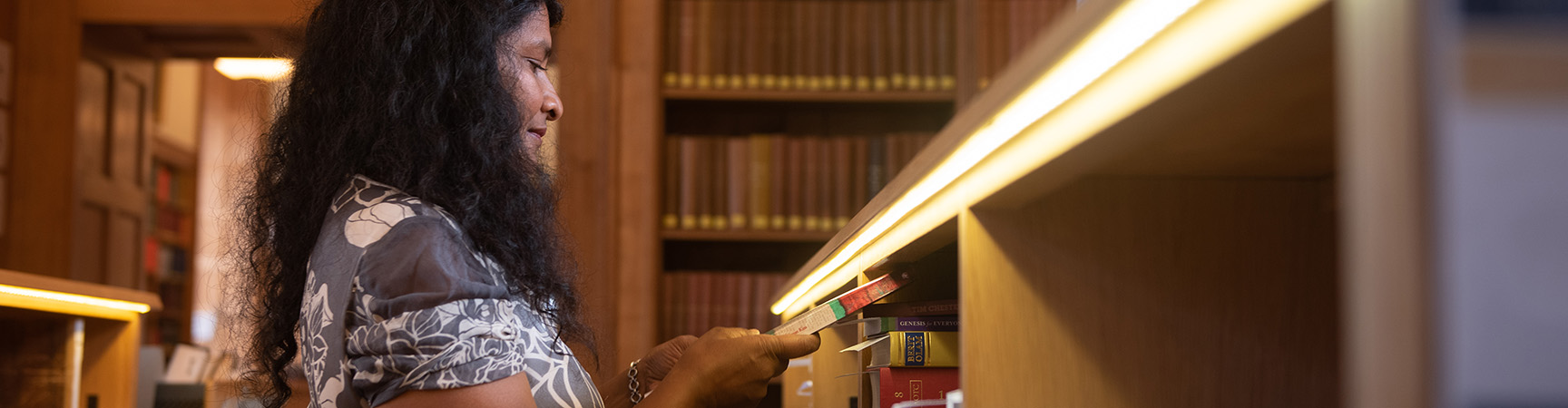 A student retrieves a book from a shelve