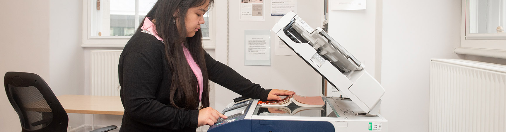 A student holds a book on a scanner