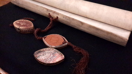 Wax seals and a rolled scroll of parchment on a black background