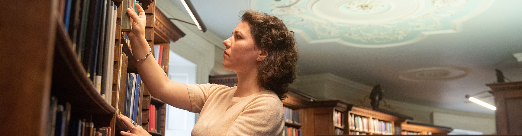 A student pulls a book off a bookshelf