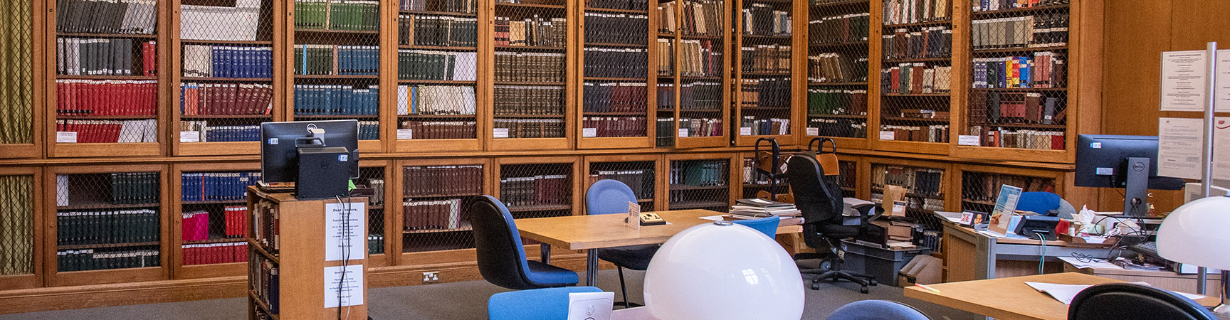 A room of desks with wooden bookshelves around the edge of the room