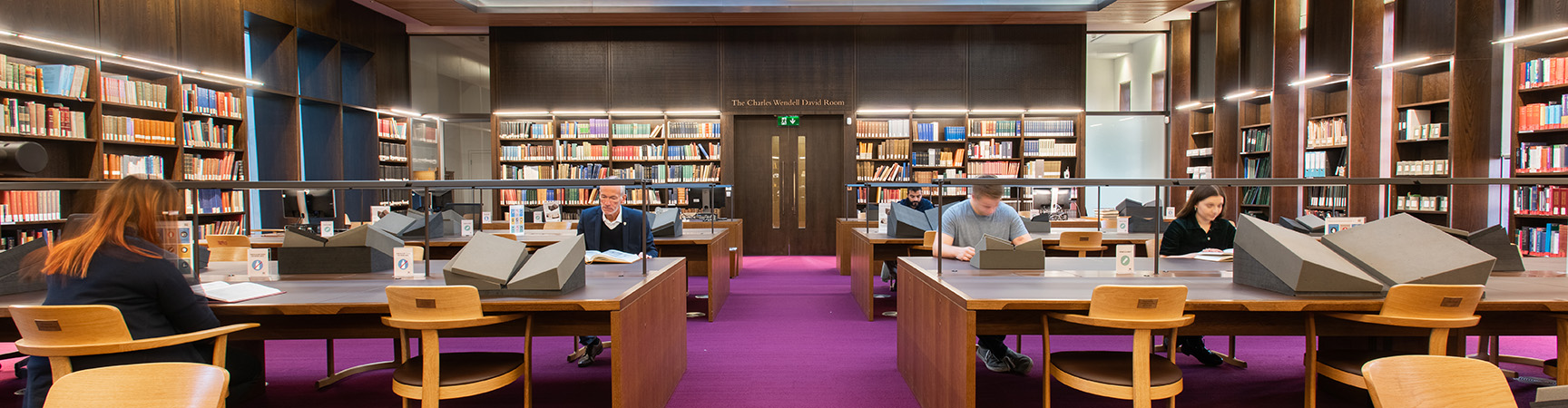 Two large desks with readers either side on a purple carpet