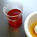 A beaker of red liquid and a pestle and mortar containing a reddish paste of ground saffron