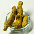 A glass dish containing three pieces of turmeric root