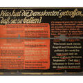 A black poster with beige and red writing in German on it - the top two corners have been restored