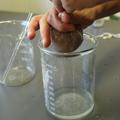A bundle of muslin is squeezed over a glass beaker