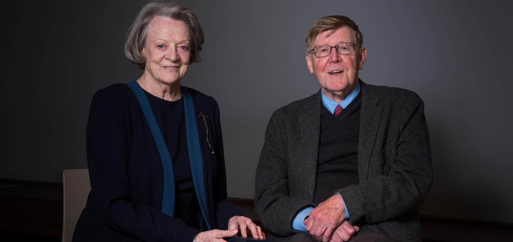 Dame Maggie Smith and Alan Bennett sit against a dark background