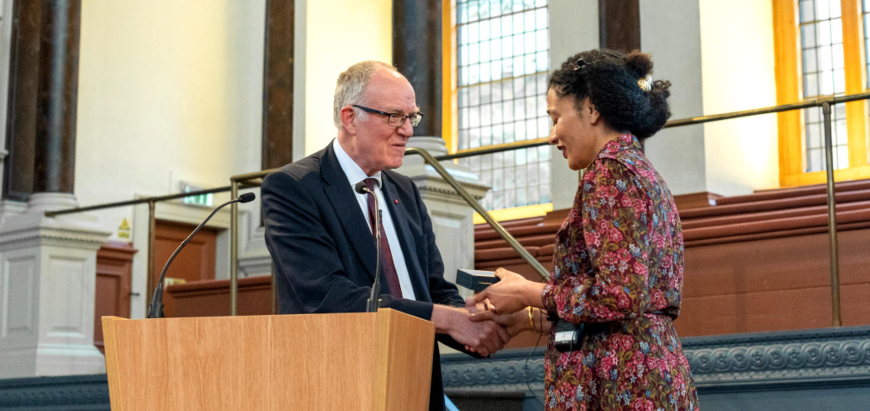 Richard Ovenden gives the Bodley Medal to Zadie Smith at a podium in the Sheldonian Theatre