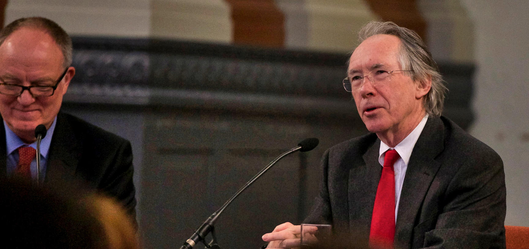 Ian McEwan sits in front of a microphone, beside Richard Ovenden