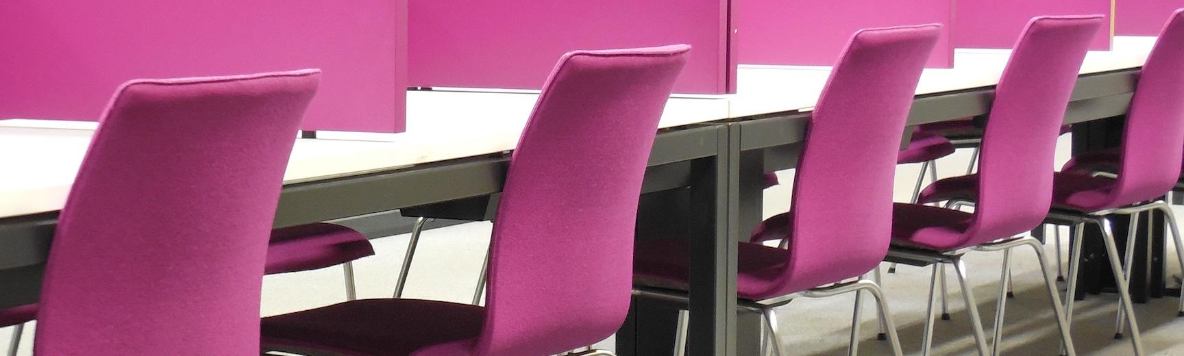 Pink chairs at tables separated by dividers