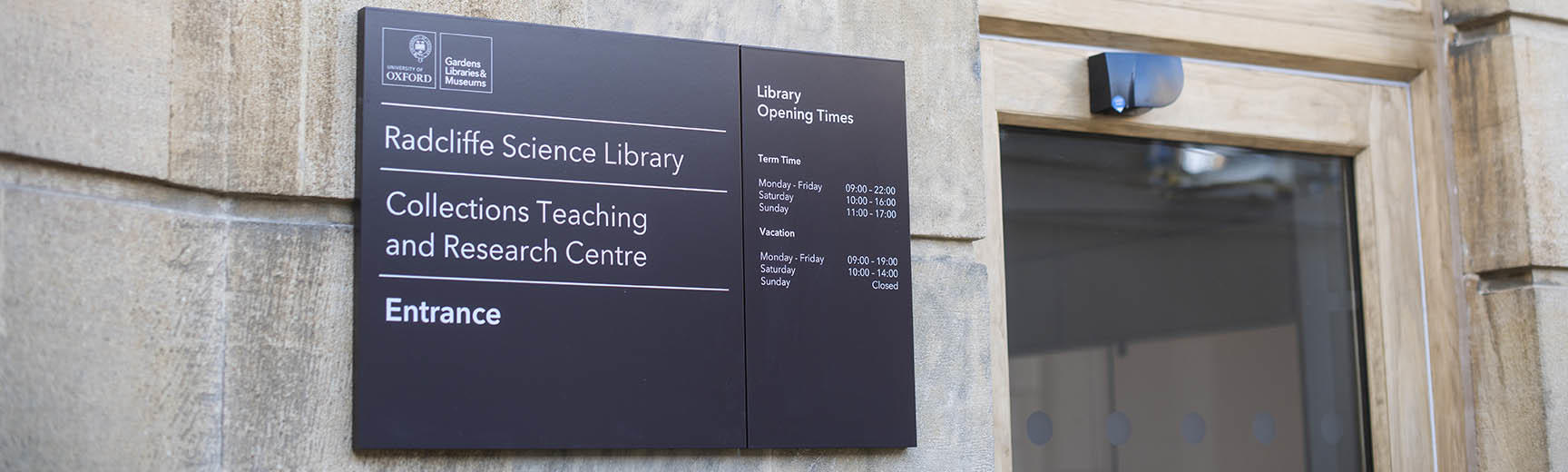The entrance to the Radcliffe Science Library with a dark blue board displaying the name and opening hours