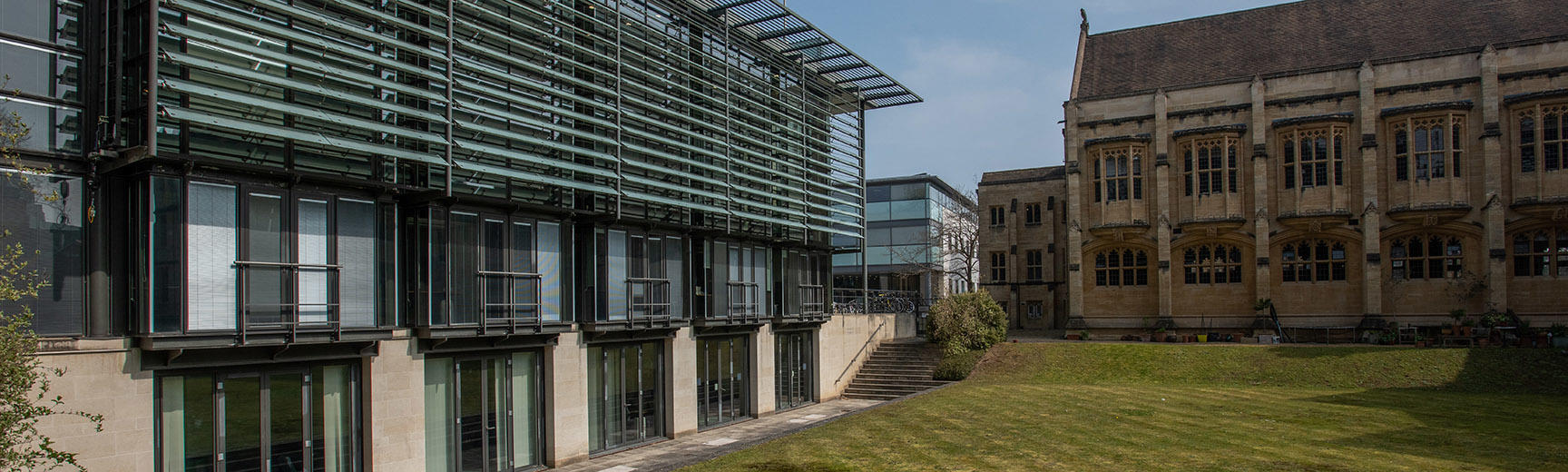 A building with grey stone at the bottom half and glass at the top half