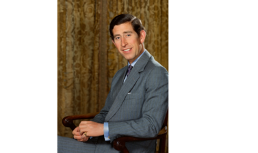 Portrait of Prince Charles - a young white male with dark hair and dressed in a grey suit, shirt & tie, sitting in a wooden chair looking straight at the camera