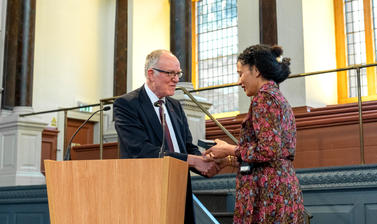 Richard Ovenden gives the Bodley Medal to Zadie Smith at a podium in the Sheldonian Theatre