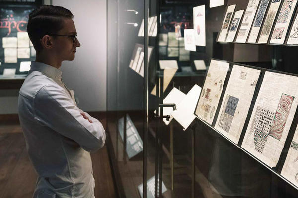 A view of an exhibition: a person looks at a glass display case - with 2D material within it