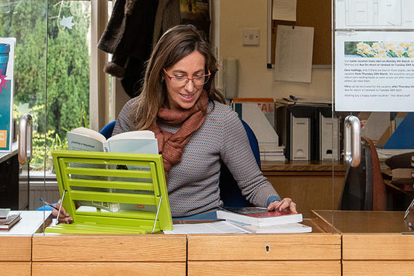 A librarian sitting behind a desk surrounded by a circular window