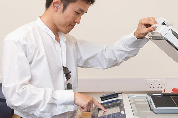 A student opening the top of a photocopier / scanner
