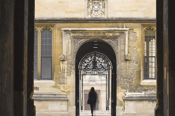 The silhouette of a person walking through an archway into the Old Bodleian Library