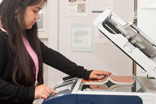 A student holds a book on a scanner