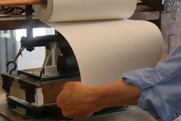 A roll of paper being fed into an old-fashioned printer