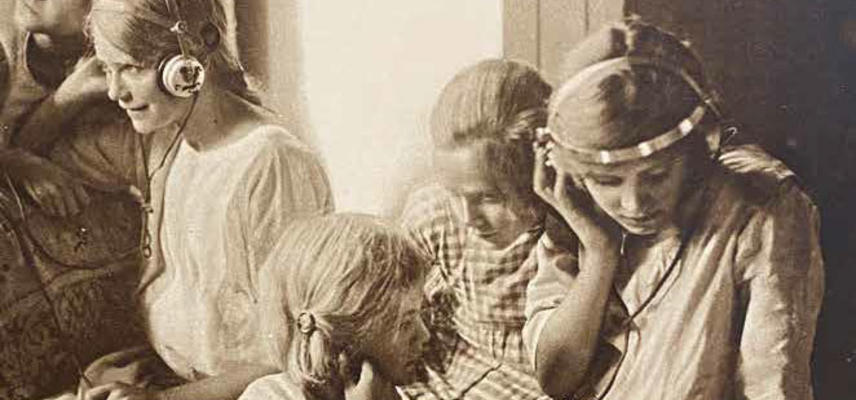 A black and white photograph of children listening to headphones
