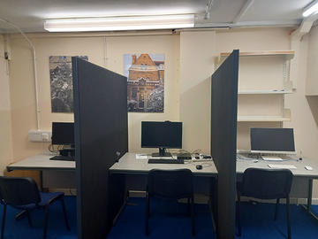 Three study spaces separated by dividers; the left-hand and centre spaces have desktop PCs, and the right-hand space has an Apple Mac