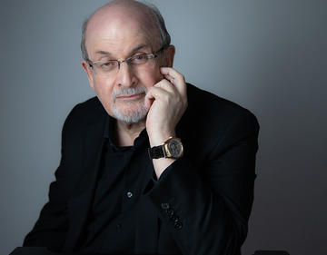 A photograph of Salman Rushdie, dressed in black