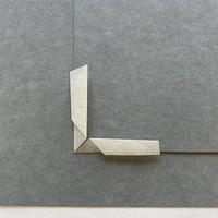 A piece of paper folded into a right angle around a gray piece of card