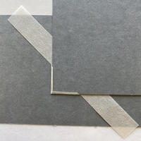 The corner of a piece of grey card with a rectangular strip of paper spread underneath