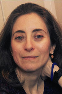 A portrait photograph of a woman with long brown hair - she looks directly at the camera