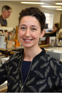 A portrait photograph of a woman with short brown hair looking directly at the camera